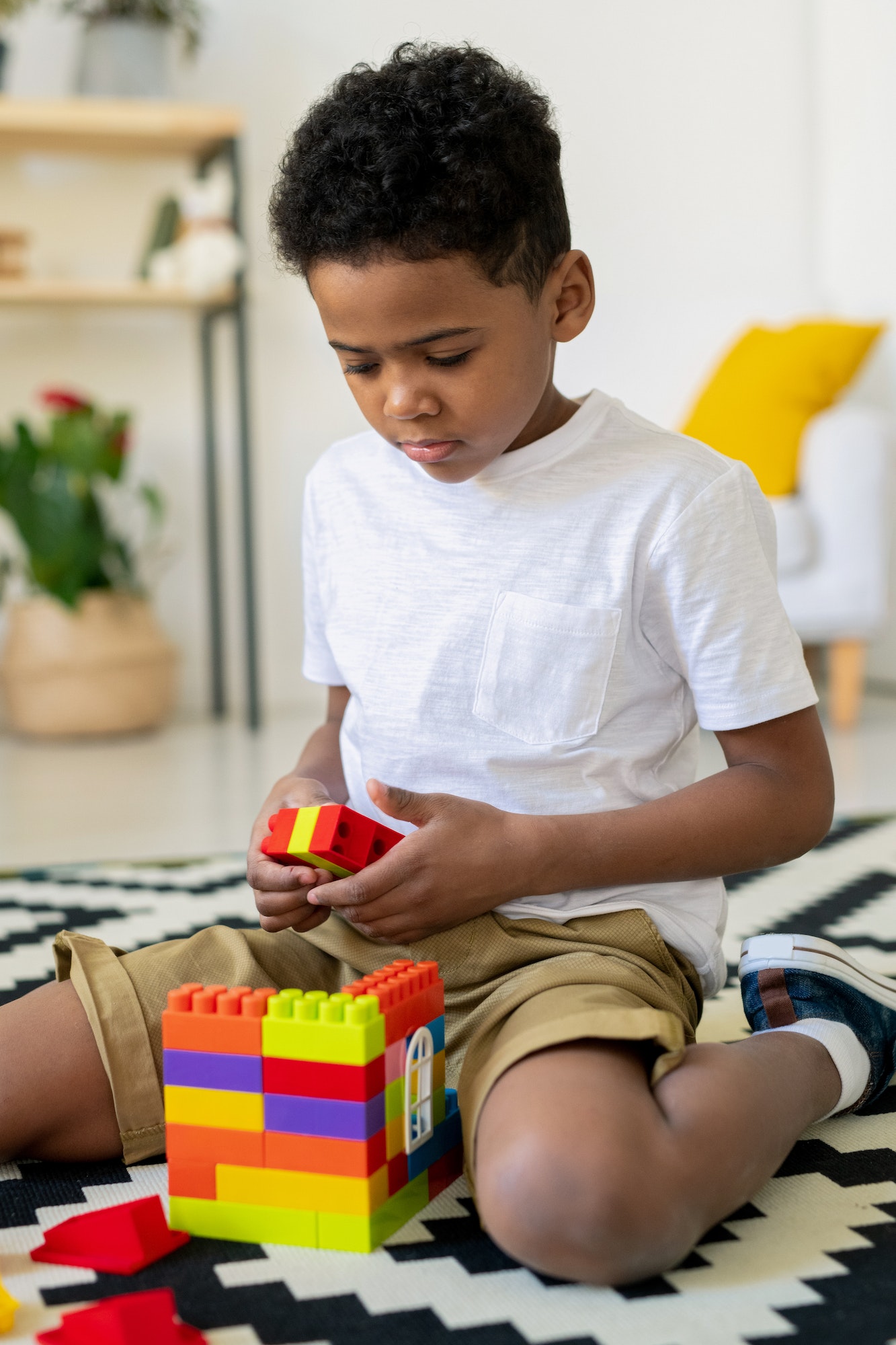 Cute African preschooler in casualwear playing on the floor in kindergarten